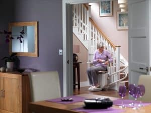 woman sitting at the bottom of a staircase in a stairlift